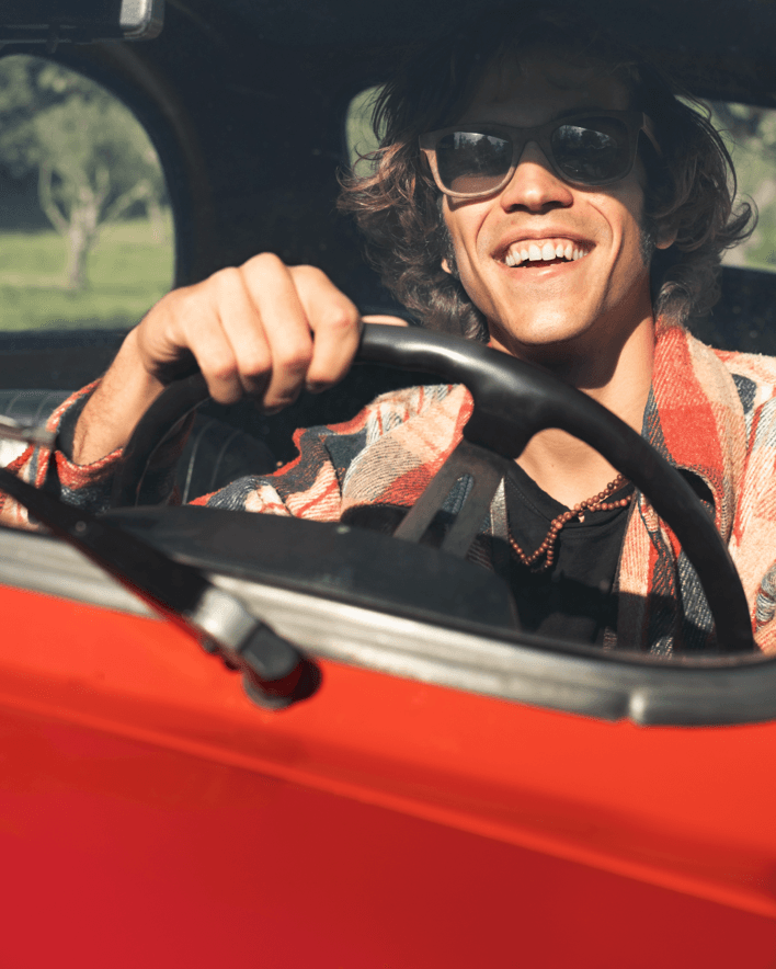 imagen de un chico sonriente conduciendo un coche de alquiler rojo para el apartado de dudas del servicio de alquiler de vehiculos de alvemacorent